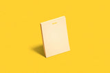 Beige notepad with 'Nest' branding on a yellow background