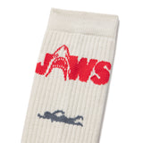 White sock with red 'Jaws' logo and blue swimmer graphic on a white background. Closeup shot of the JAWS logo from the academy award winning movie JAWS 50th ANNIVERSARY | ACADEMY MUSEUM