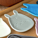 Set of ceramic dishes shaped like Totoro characters on a wooden surface