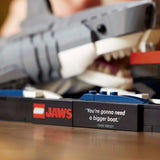 Close-up of a LEGO JAWS set with  a shark and text box on a wooden  Jaws (1975) 50th Anniversary Lego Setsurface.