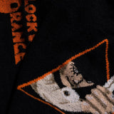 Close-up of a black sock with orange text and a geometric pattern.