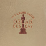 Embroidered Oscar statue and text on a beige fabric background