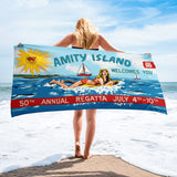 Person holding a beach towel with 'Amity Island' and '50th Annual Regatta' design on a beach.